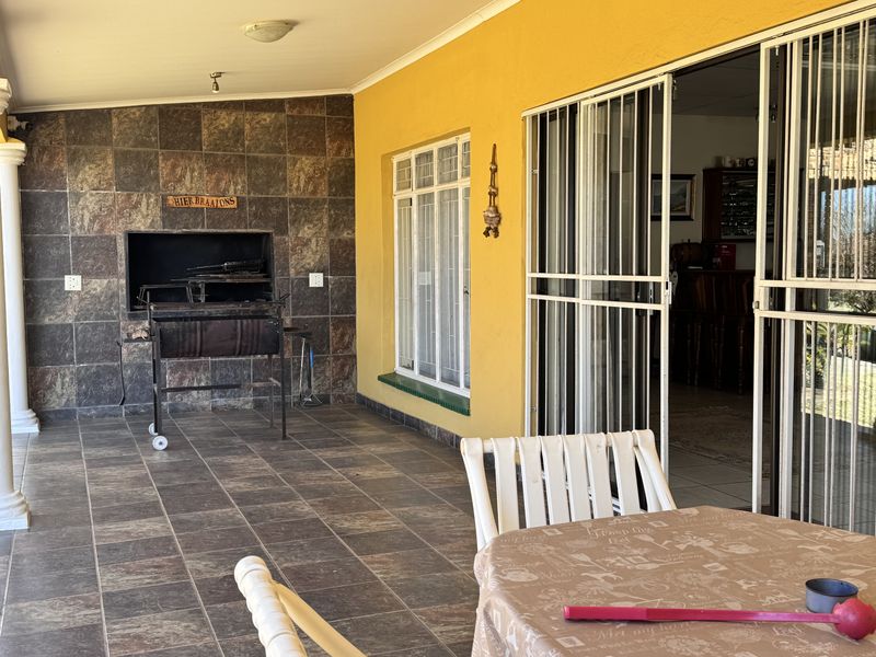 Covered patio area featuring a built-in braai, stone-clad feature wall, and direct access to the interior through sliding security doors.