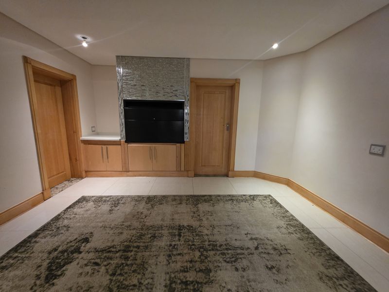 A spacious living area featuring a built-in fireplace with mosaic detailing, wooden door frames, and neutral tiled flooring.