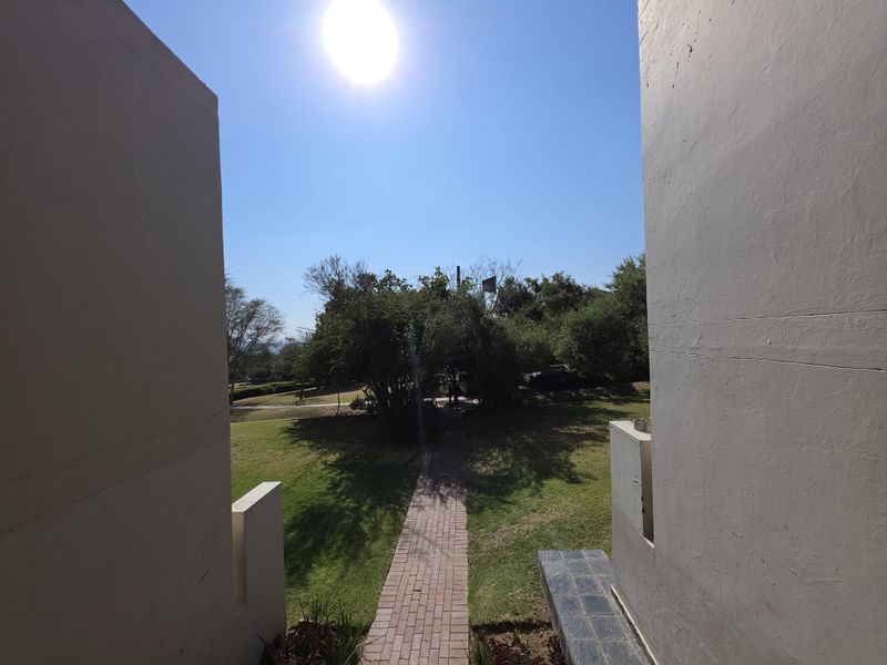 A view from the property looking out onto a private garden area with a paved walkway and established greenery.