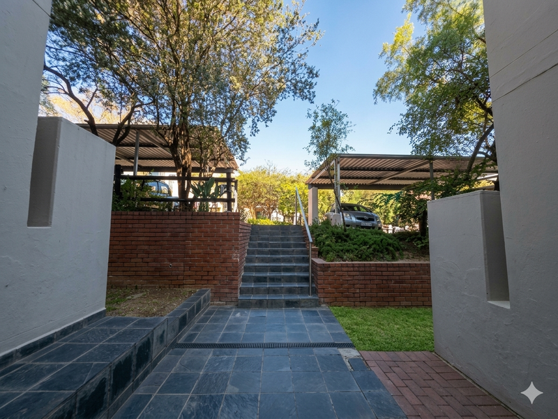 Rear exterior area featuring a tiled staircase, brick retaining walls, and covered carport parking spaces with paved access.