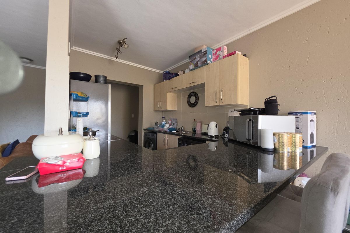 Kitchen area featuring a large granite breakfast bar, built-in cabinetry, and tiled backsplash, providing a functional workspace within an open-plan layout.