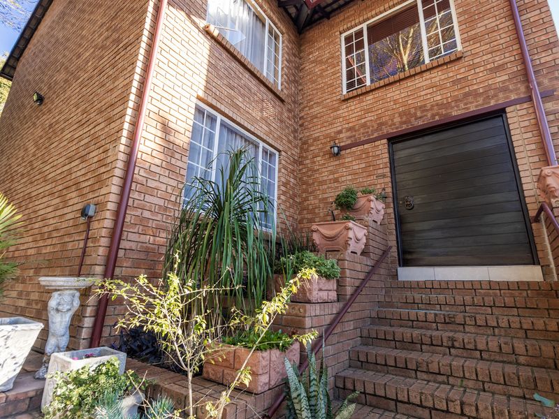 Front entrance of a townhouse featuring a brick facade, a solid timber door, and a brick staircase with a metal handrail.