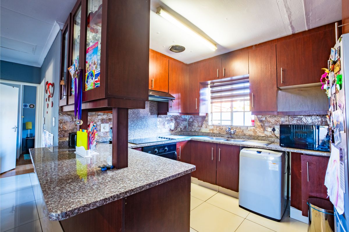 A functional kitchen featuring dark wood cabinetry, granite countertops, a breakfast bar, and tiled flooring, offering a practical layout for daily meal preparation.