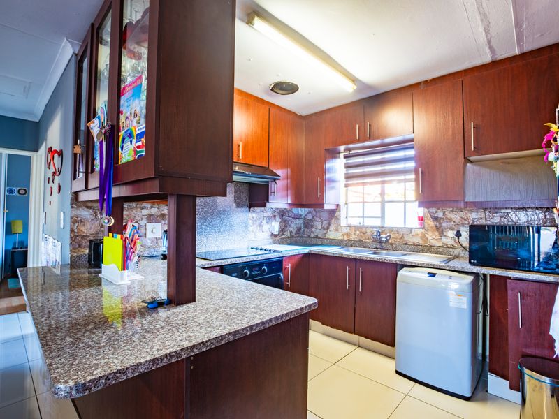 A functional kitchen featuring dark wood cabinetry, granite countertops, a breakfast bar, and tiled flooring, offering a practical layout for daily meal preparation.