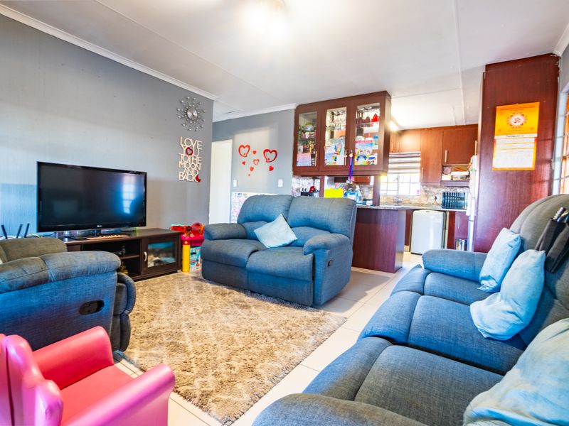 Open-plan living area featuring tiled floors and a functional kitchen with built-in cabinetry and a breakfast counter.