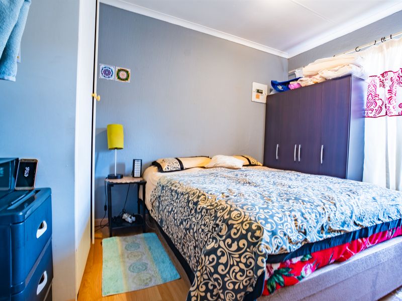 A functional bedroom featuring laminate flooring, a built-in wardrobe, and coved ceiling details.