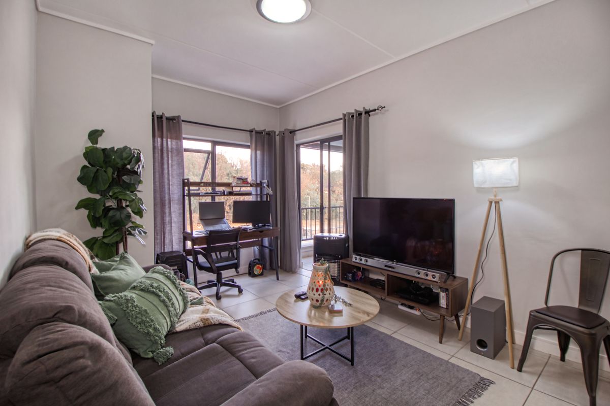 A well-lit living room featuring tiled flooring, neutral walls, and sliding glass doors that provide access to an outdoor area.