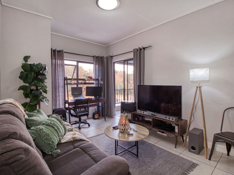 A well-lit living room featuring tiled flooring, neutral walls, and sliding glass doors that provide access to an outdoor area.
