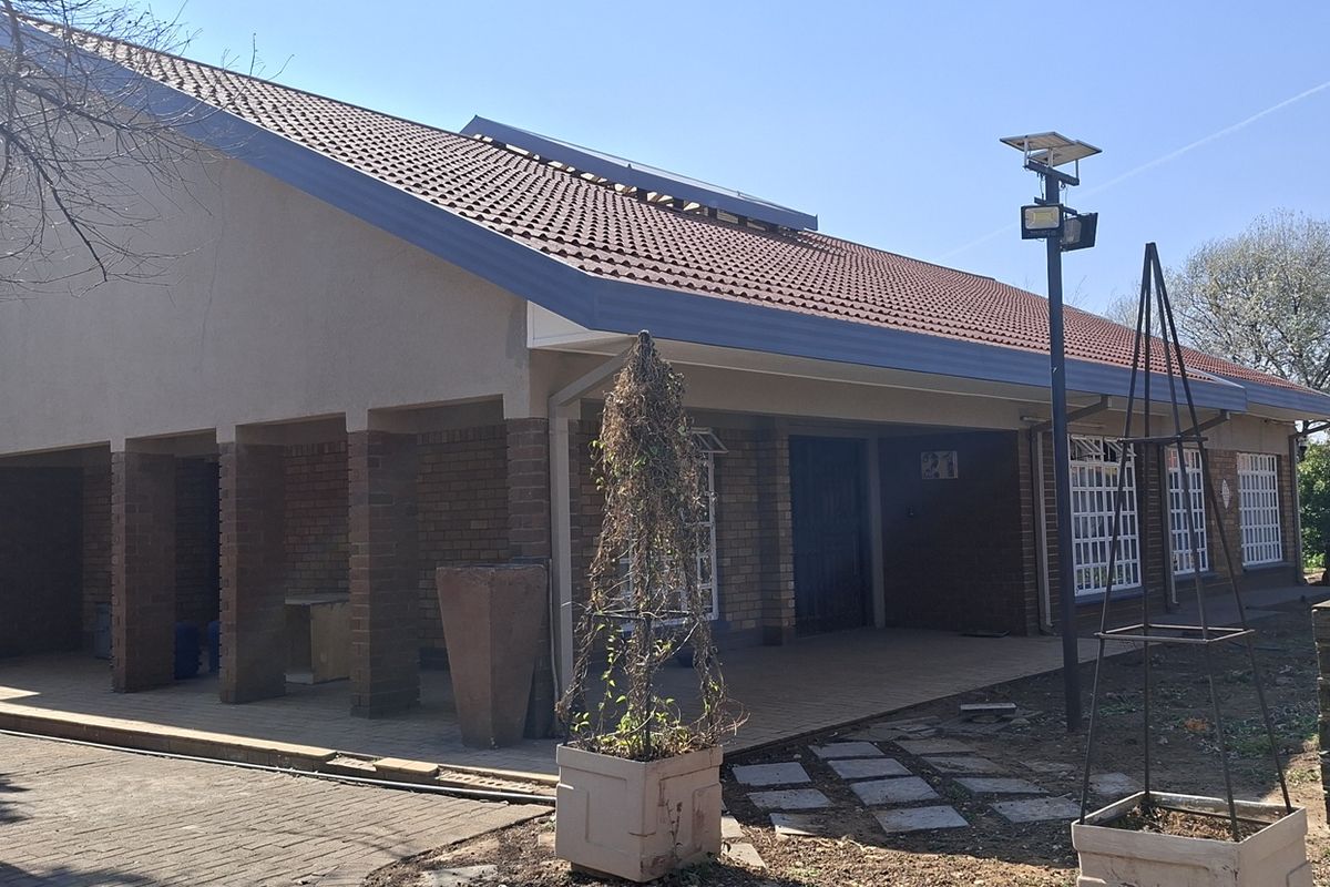 Rear view of the house featuring a covered patio area, brick exterior walls, and a tiled roof with solar lighting.