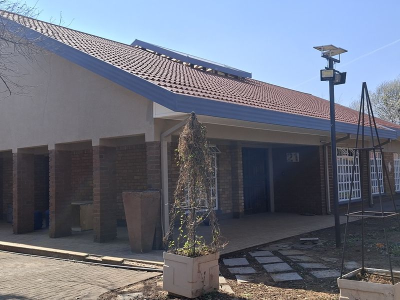 Rear view of the house featuring a covered patio area, brick exterior walls, and a tiled roof with solar lighting.