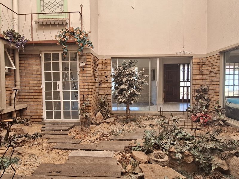 A central courtyard or atrium area featuring brick walls, sliding glass doors, and a landscaped stone garden with a stepped pathway.