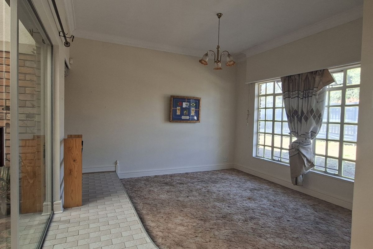 Spacious living area featuring carpeted flooring, a brick feature wall, and large grid-pattern windows providing natural light.