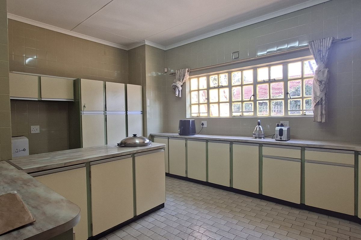 A spacious, dated kitchen featuring extensive built-in cabinetry, tiled walls, and ample counter space, offering significant potential for a modern renovation.