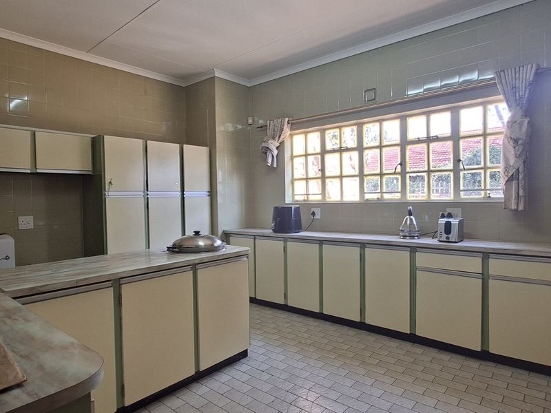 A spacious, dated kitchen featuring extensive built-in cabinetry, tiled walls, and ample counter space, offering significant potential for a modern renovation.