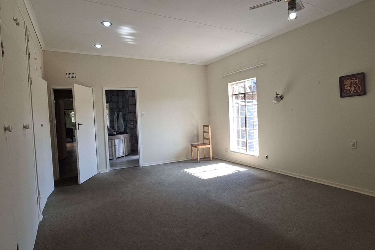 Spacious bedroom featuring extensive built-in cupboards, recessed lighting, a ceiling fan, and direct access to an en-suite bathroom.
