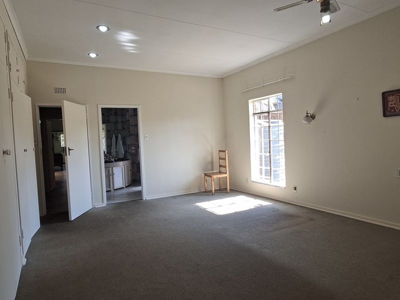 Spacious bedroom featuring extensive built-in cupboards, recessed lighting, a ceiling fan, and direct access to an en-suite bathroom.