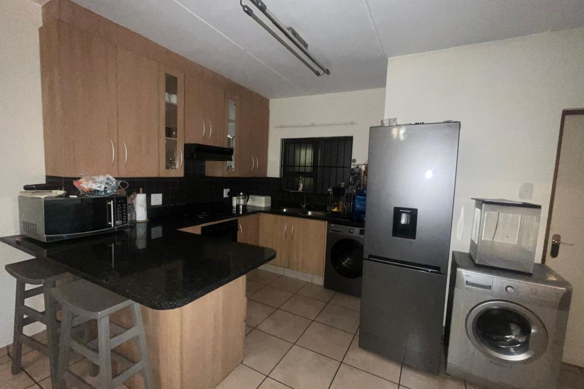 A functional kitchen featuring granite countertops, wood-finish cabinetry, tiled flooring, and a breakfast nook area, providing a practical layout for daily use.