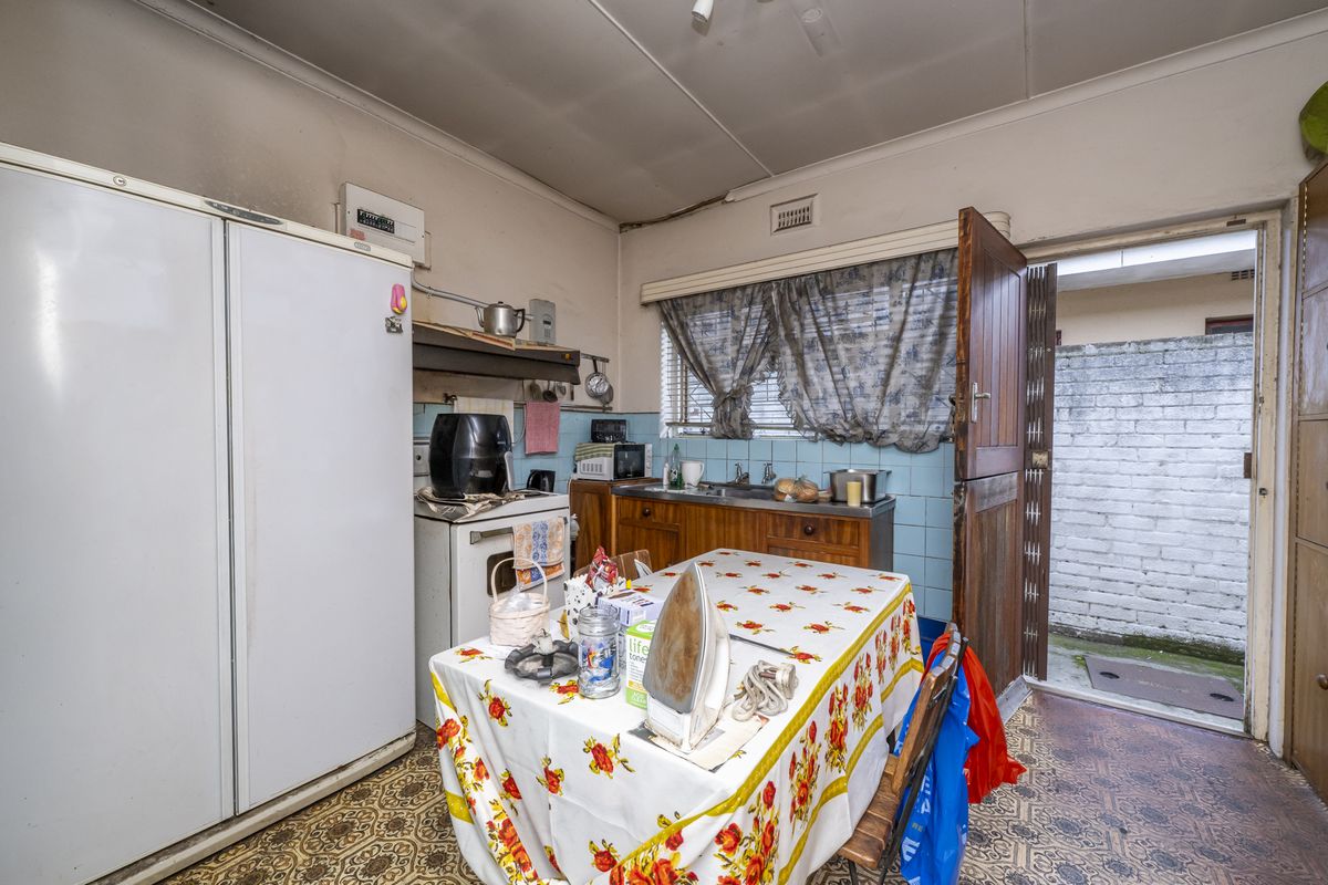 A dated kitchen featuring original cabinetry, a freestanding stove, and direct access to an exterior courtyard area.