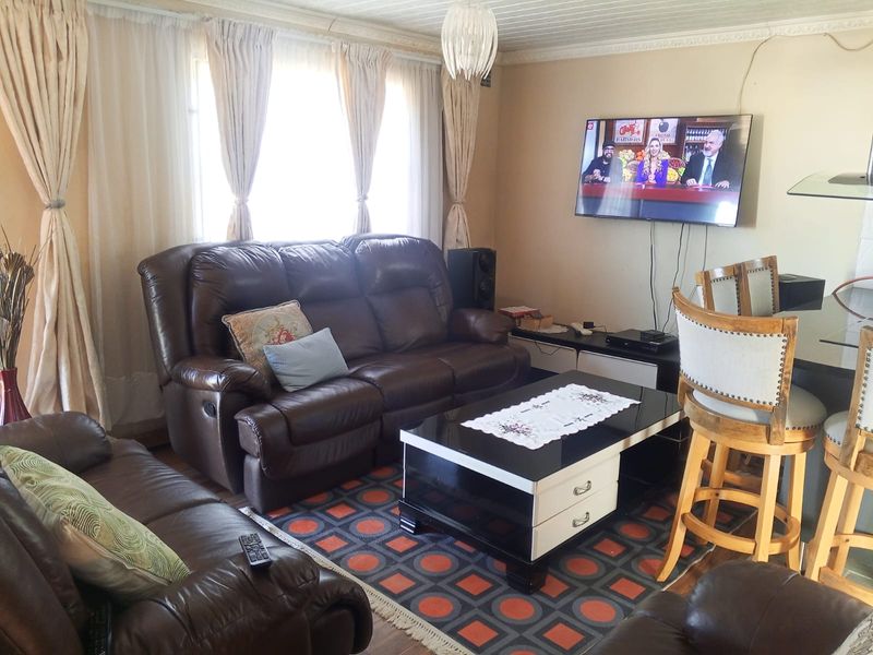 A living room featuring a tongue and groove ceiling, coving, and a wall-mounted television.