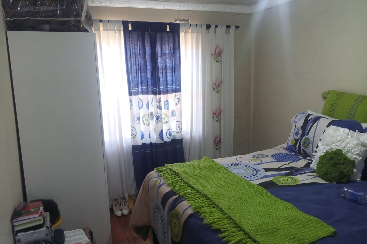 A bedroom featuring crown molding and a window, currently showing signs of wear on the wall surfaces.