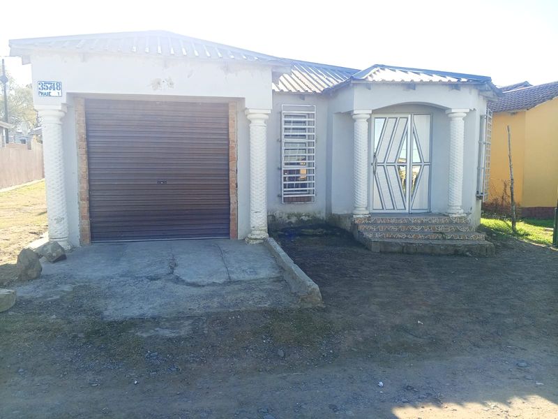 Front elevation of a single-story house featuring a roller garage door, decorative columns, and a secure entrance with tiled steps.