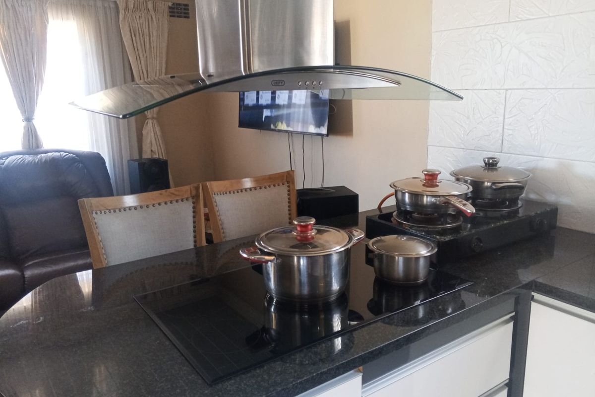 A modern kitchen island featuring a sleek granite countertop, integrated induction hob, and a stainless steel extractor fan, providing a functional cooking space.