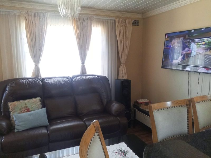 A comfortable living room featuring decorative crown molding, recessed ceiling lighting, and a wall-mounted television setup.
