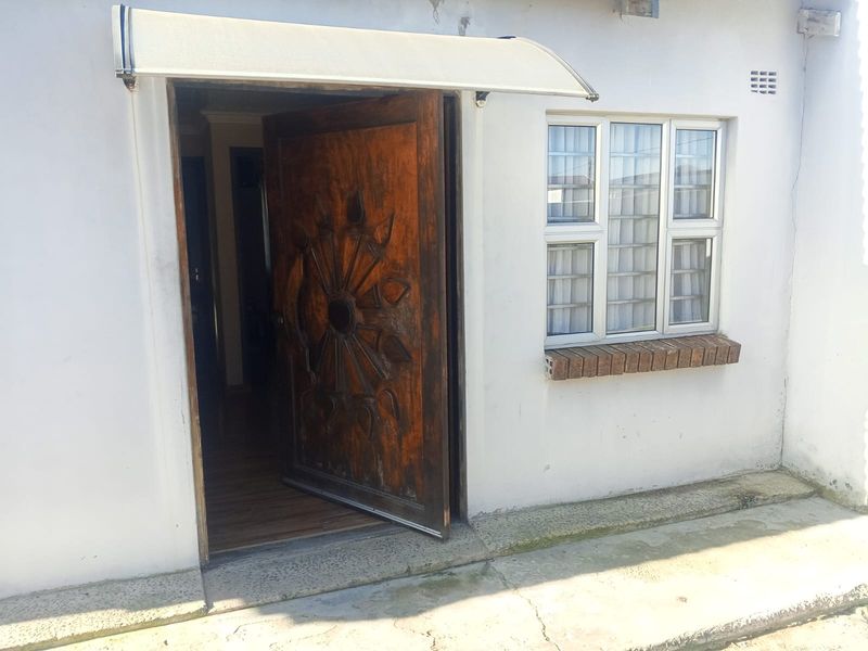 Front entrance featuring a decorative carved wooden door, an overhead awning, and an aluminium window with a brick sill.