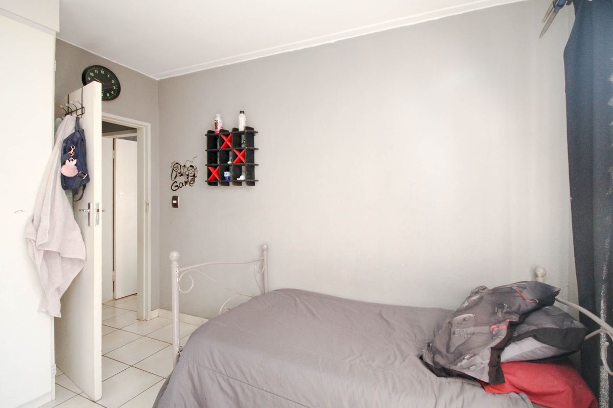 A standard bedroom featuring tiled flooring and neutral wall finishes, providing a functional space with direct access to the hallway.