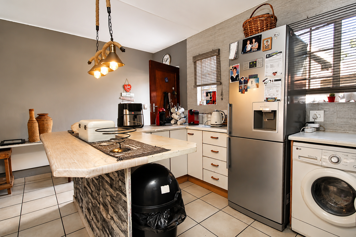A functional kitchen featuring a central island, tiled flooring, and built-in cabinetry, providing a practical workspace with integrated appliance connections.