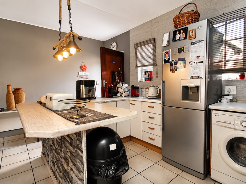 A functional kitchen featuring a central island, tiled flooring, and built-in cabinetry, providing a practical workspace with integrated appliance connections.