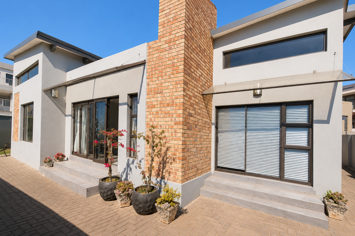 Modern rear exterior featuring a prominent brick chimney, paved patio area, and large sliding glass doors providing seamless indoor-outdoor flow.