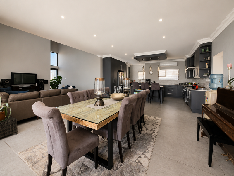 Spacious open-plan living area featuring a modern kitchen with dark cabinetry, a central island, tiled floors, and recessed lighting throughout.