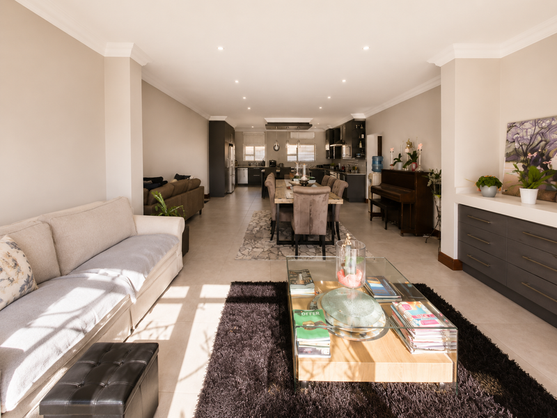 Spacious open-plan living and dining area featuring tiled floors, recessed lighting, and a modern kitchen with built-in cabinetry and integrated appliances.