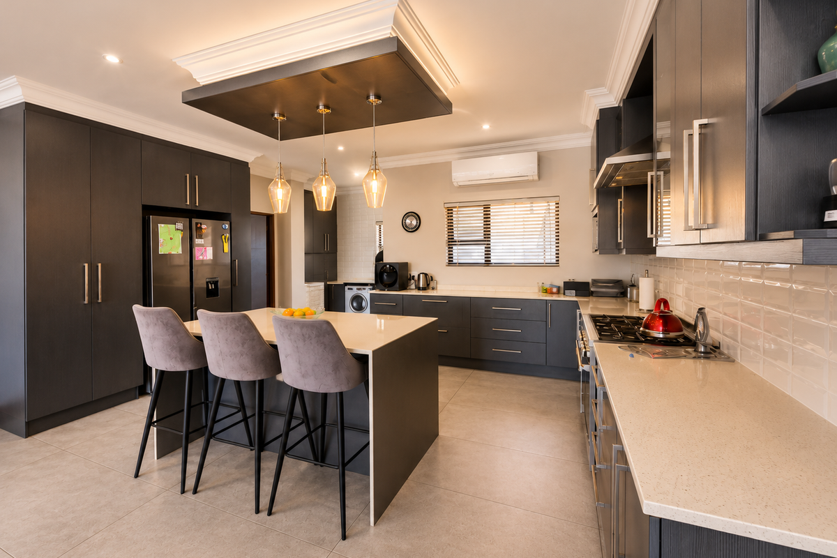 Modern kitchen featuring dark cabinetry, quartz countertops, a central island with pendant lighting, subway tile backsplash, and integrated appliances.
