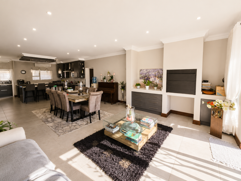Spacious open-plan living and dining area featuring a modern kitchen, built-in fireplace, and neutral tiled flooring throughout.