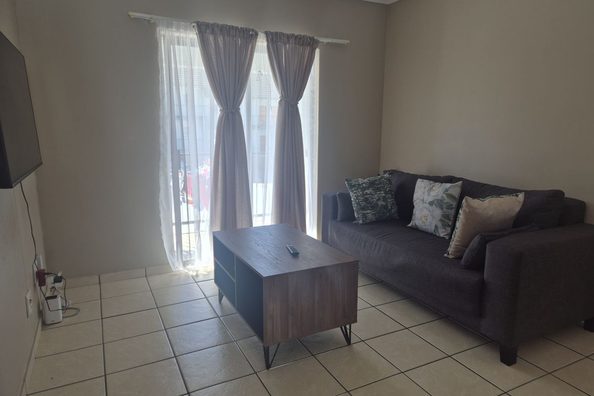 A living room featuring tiled flooring and a sliding glass door providing natural light.