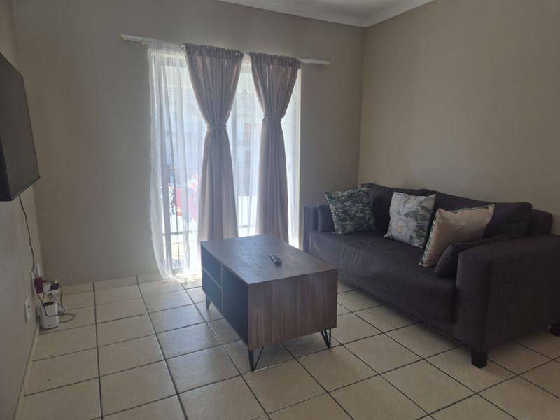 A living room featuring tiled flooring and a sliding glass door providing natural light.