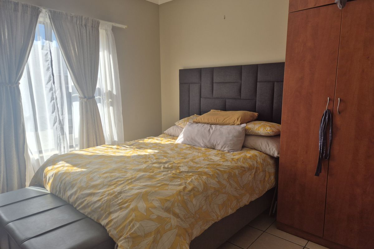 A bedroom featuring tiled flooring and a built-in wardrobe, with natural light entering through the window.