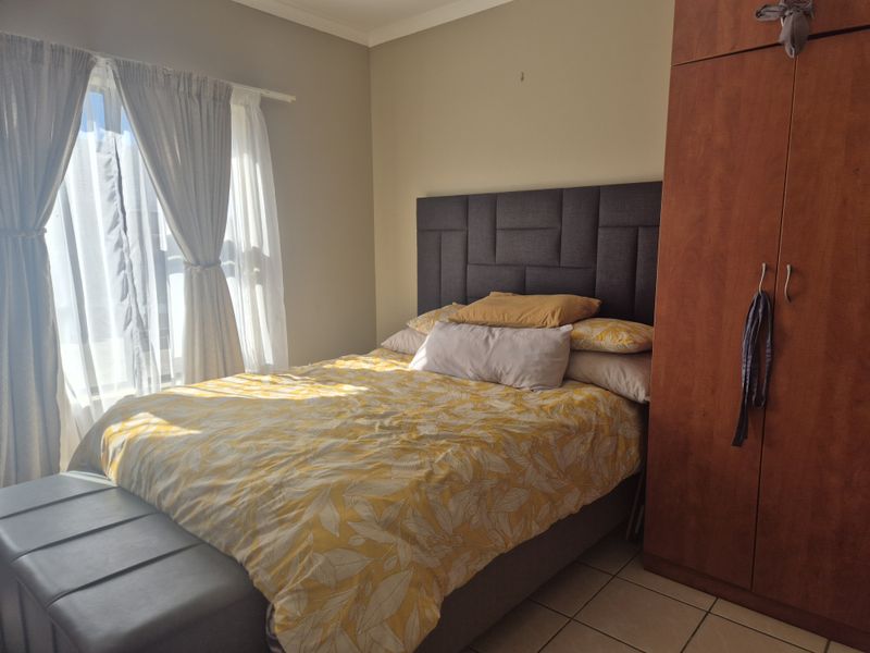 A bedroom featuring tiled flooring and a built-in wardrobe, with natural light entering through the window.