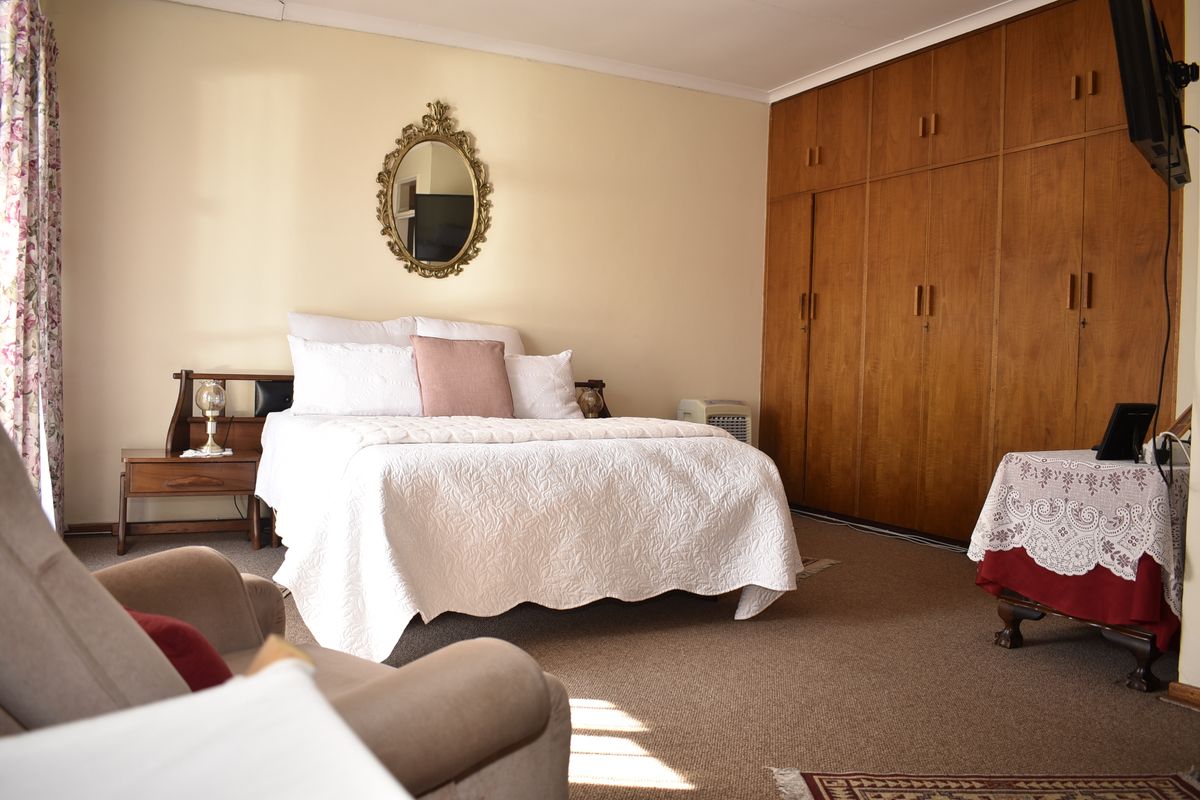 A spacious bedroom featuring extensive built-in wooden cabinetry and neutral carpeting, offering a functional layout with ample storage space.