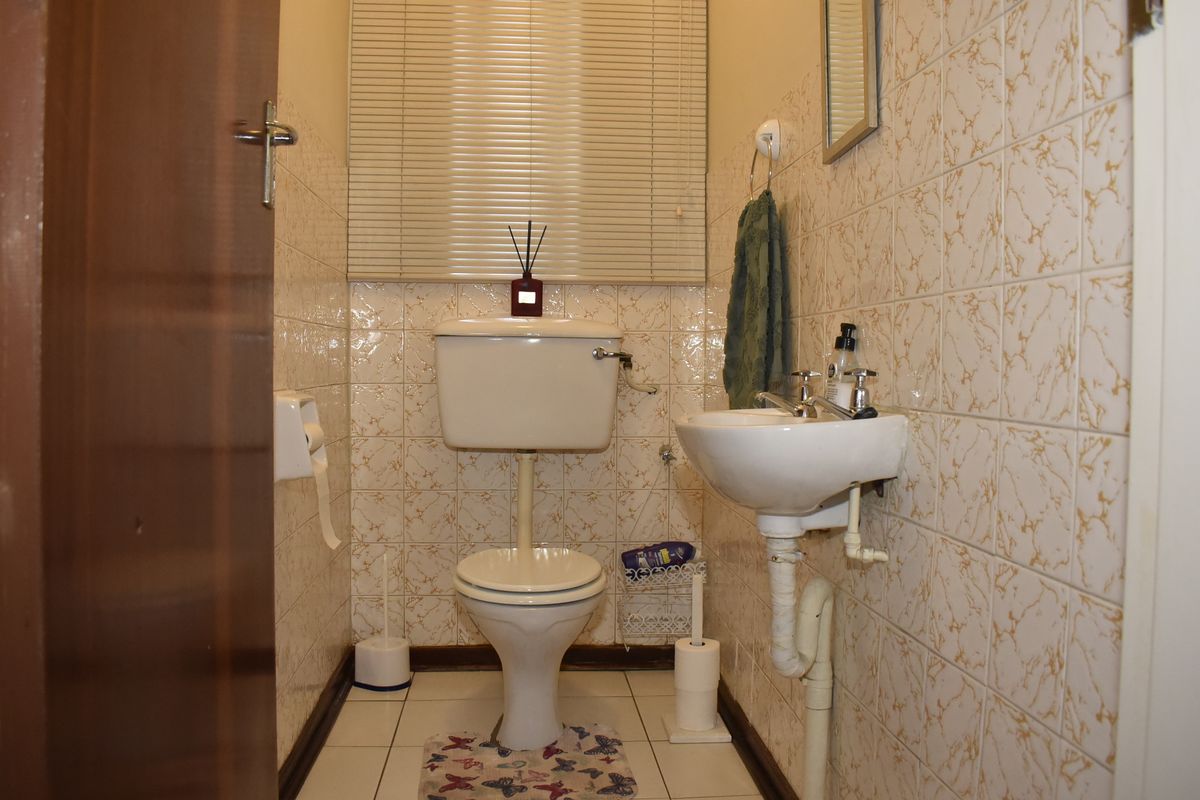 A compact guest bathroom featuring a standard toilet, pedestal basin, and dated wall tiling.