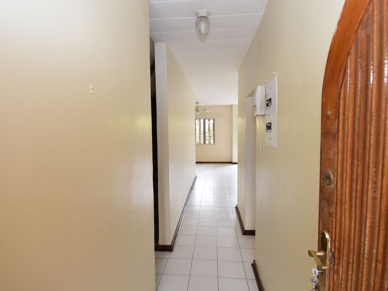 A vacant entrance hallway featuring tiled flooring and access to the main living area, providing a clean canvas for interior design.