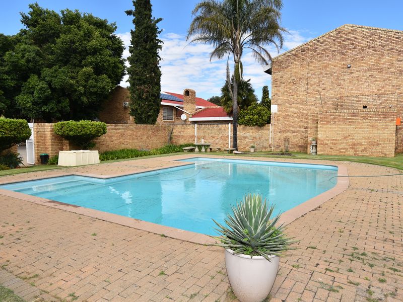 Outdoor pool area featuring a swimming pool, paved surround, and brick boundary walls within a townhouse complex setting.