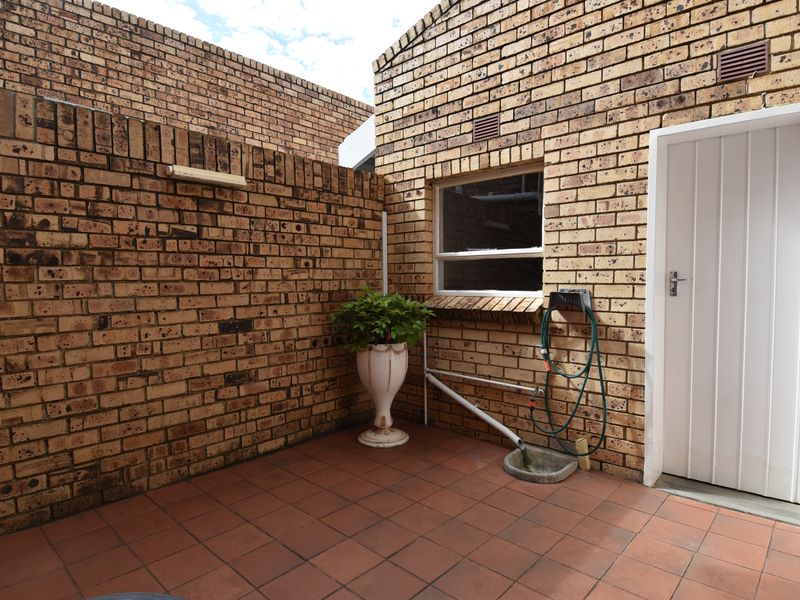 A private rear courtyard featuring face brick walls, tiled flooring, and direct access to the property via an external door.