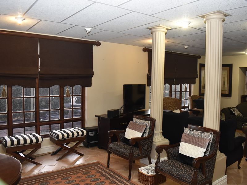 Spacious living area featuring decorative columns, tiled flooring, and large timber-framed windows, offering a traditional aesthetic with potential for modern updates.