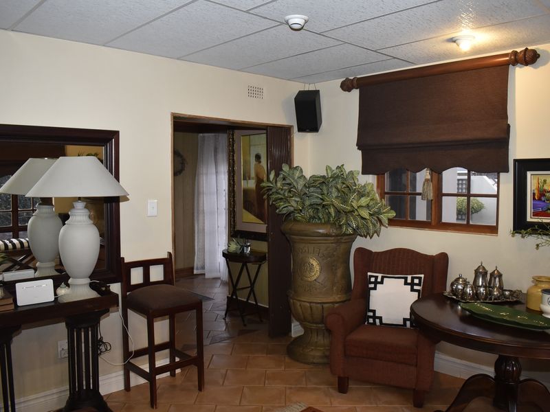 A living area featuring tiled flooring, a drop ceiling, and timber window frames, providing a traditional aesthetic with potential for modern updates.