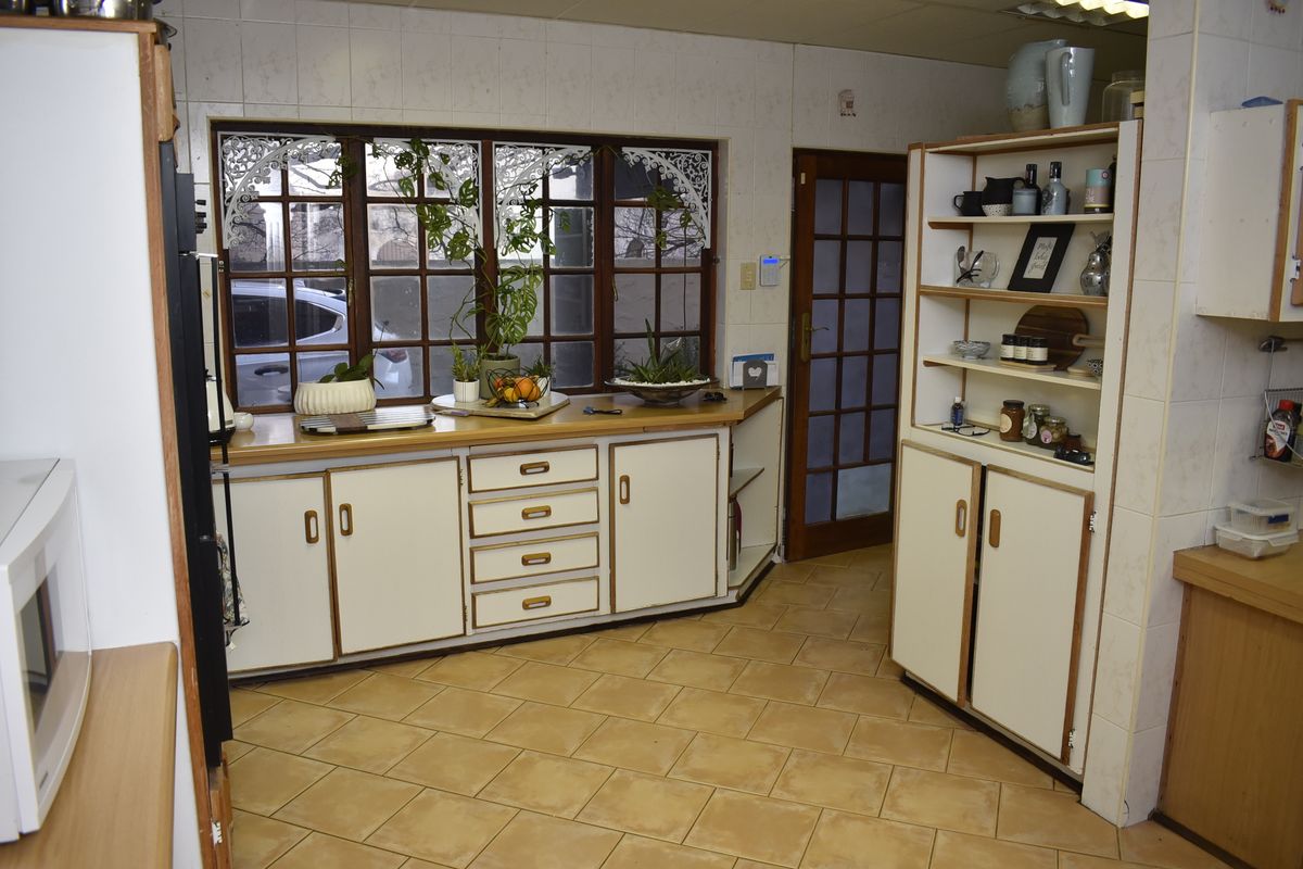 A functional kitchen featuring built-in cabinetry, tiled flooring, and large timber-framed windows that provide natural light.