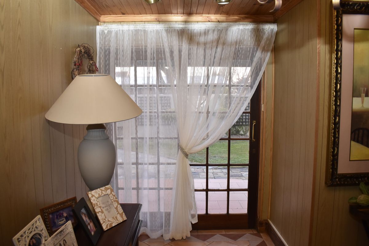 A living area featuring timber wall paneling, a timber ceiling, and a classic french door providing access to the outdoor patio area.