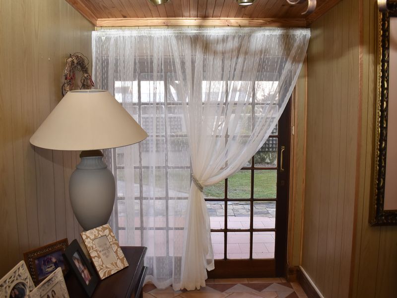 A living area featuring timber wall paneling, a timber ceiling, and a classic french door providing access to the outdoor patio area.